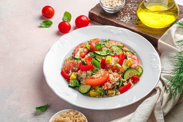 Foto uma porção de salada com tomate quinoa abacate e pepino e pimenta vermelha em um fundo claro salada tabbouleh espaço de cópia de vista lateral