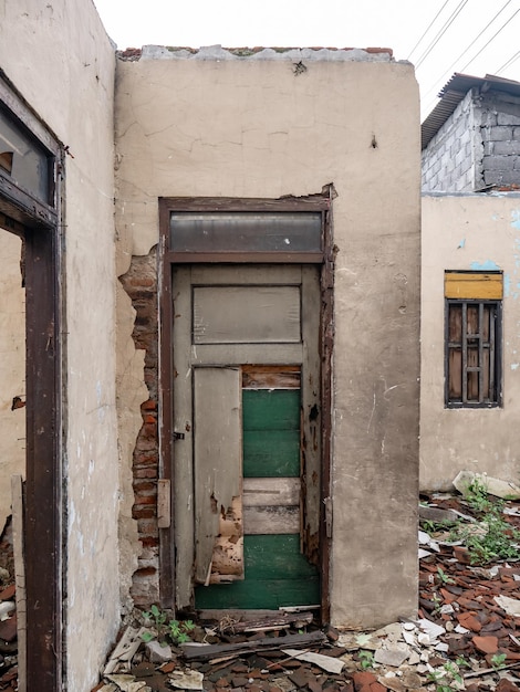 Uma porta quebrada numa casa que está abandonada há muito tempo.