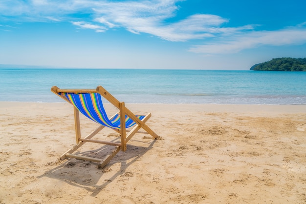 Uma praia cadeiras na areia branca com céu azul e mar de verão