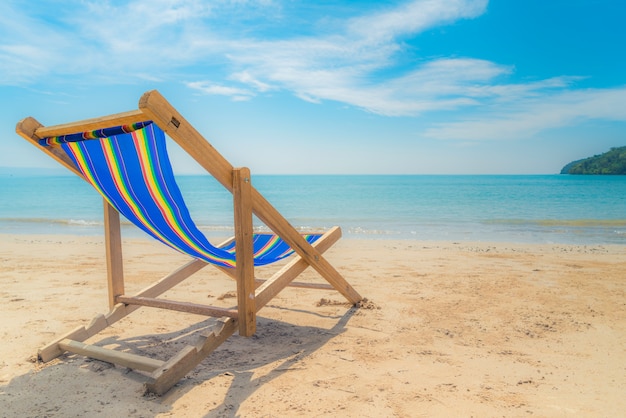 Uma praia cadeiras na areia branca com céu azul e mar de verão