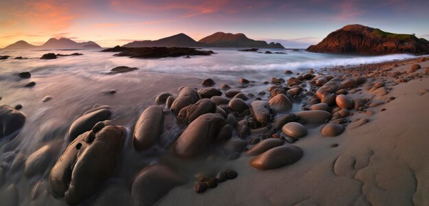 Uma praia com pedras e o céu ao pôr do sol