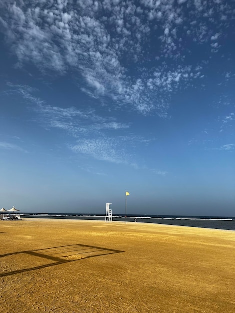 Uma praia com um céu azul e uma duna de areia amarela.