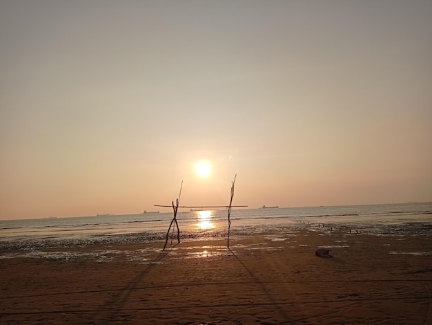 Uma praia com um pôr do sol e dois postes