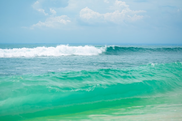 Uma praia de areia tropical ideal para surfar no oceano. Água turquesa bonita e ondas.