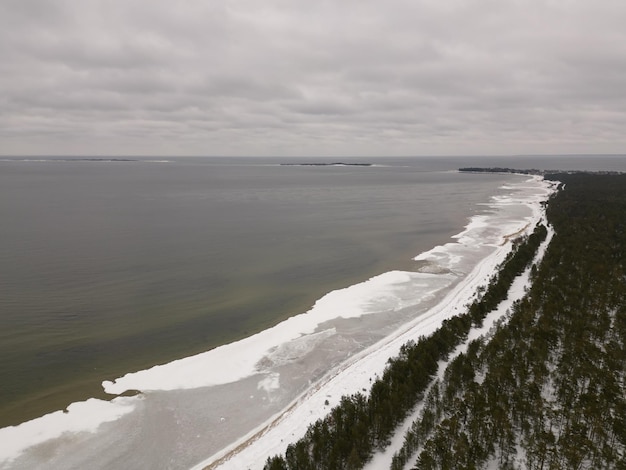 Uma praia de neve com uma estrada e árvores em primeiro plano.