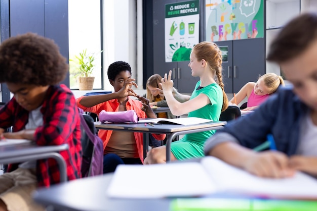 Uma professora de escola feliz e diversa e uma estudante a praticar a linguagem de sinais na sala de aula