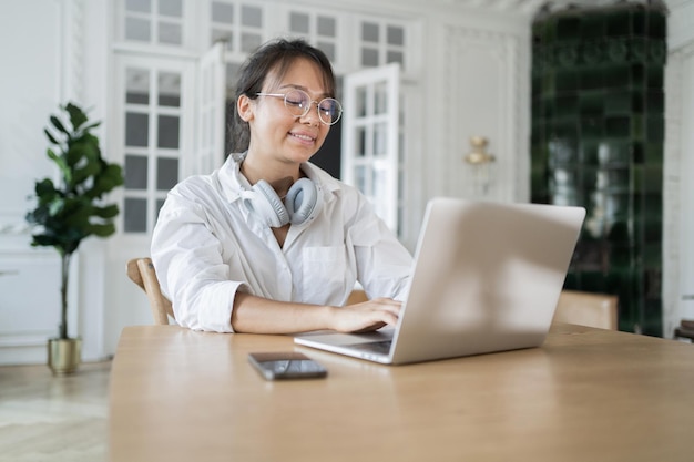 Uma programadora feminina usa um laptop Workplace no novo relatório on-line do escritório