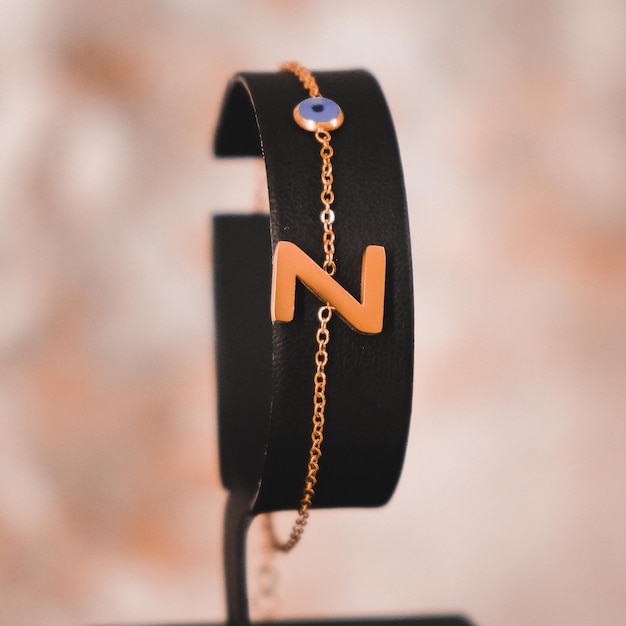 Uma pulseira com a letra n é exibida em um suporte.