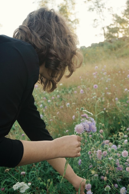 Foto uma rapariga a colher flores no campo.