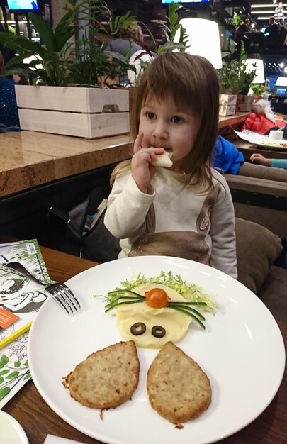 Foto uma rapariga a comer no restaurante.