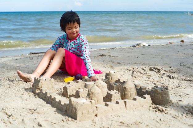 Uma rapariga a fazer um castelo de areia na praia.