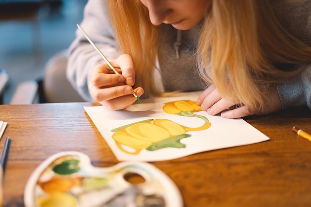 Uma rapariga adolescente bonita desenha um quadro com tinta de cartaz