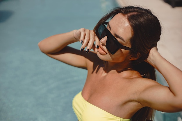 Foto uma rapariga bem beijada a posar na piscina.