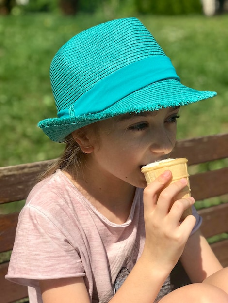 Foto uma rapariga bonita a comer gelado sentada num banco.