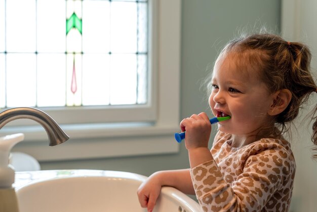 Foto uma rapariga bonita a escovar os dentes em casa.