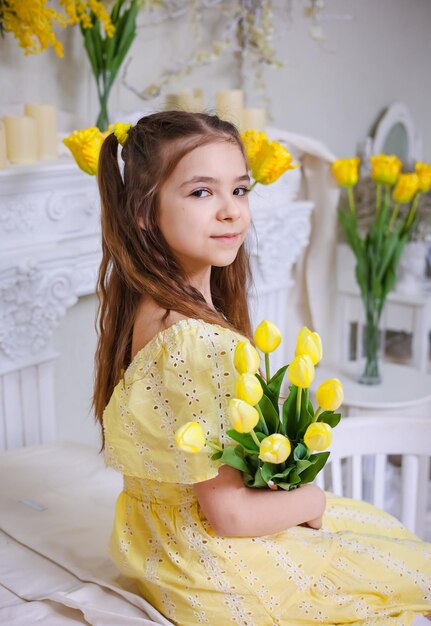 Uma rapariga bonita com um vestido amarelo e um buquê de tulipas amarelas.