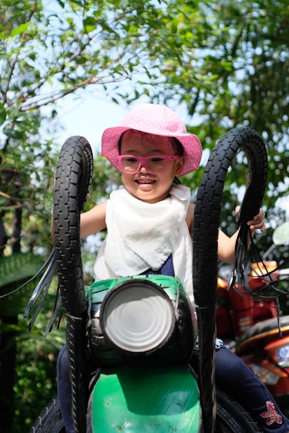 Foto uma rapariga bonita sentada numa moto de brinquedo.