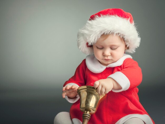 Uma rapariga bonita vestida de Pai Natal contra um fundo cinzento.