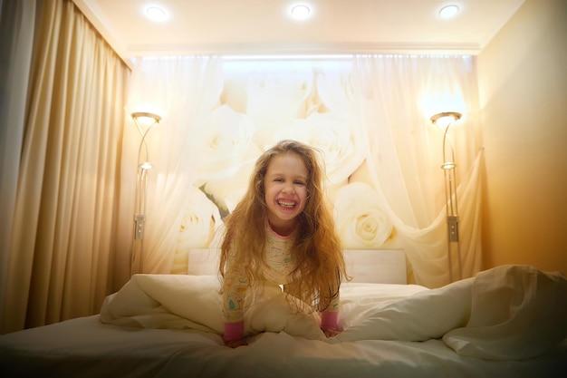 Uma rapariga feliz a divertir-se num quarto de hotel, numa viagem com uma criança turista.