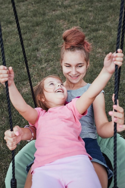Uma rapariga feliz no baloiço no parque infantil
