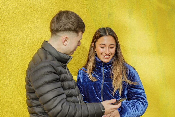 Foto uma rapariga latina a conversar com um rapaz sobre um fundo amarelo.