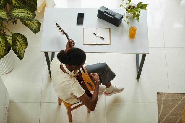 Foto uma rapariga negra criativa a tocar guitarra.