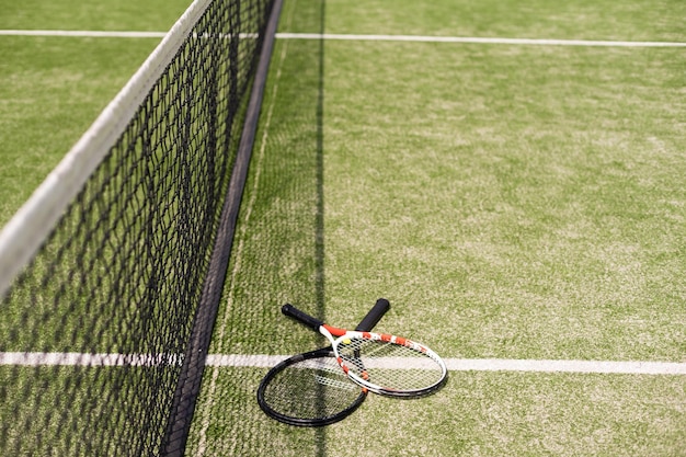 Uma raquete de tênis e uma nova bola de tênis em uma quadra de tênis recém-pintada