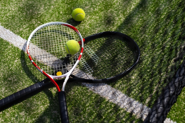 Uma raquete de tênis e uma nova bola de tênis em uma quadra de tênis recém-pintada