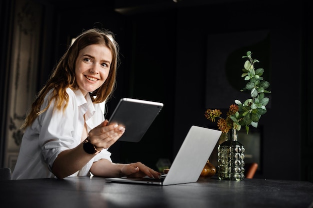 Uma recepcionista feminina trabalha em um local de trabalho de hotel usa um laptop se comunicando com um cliente