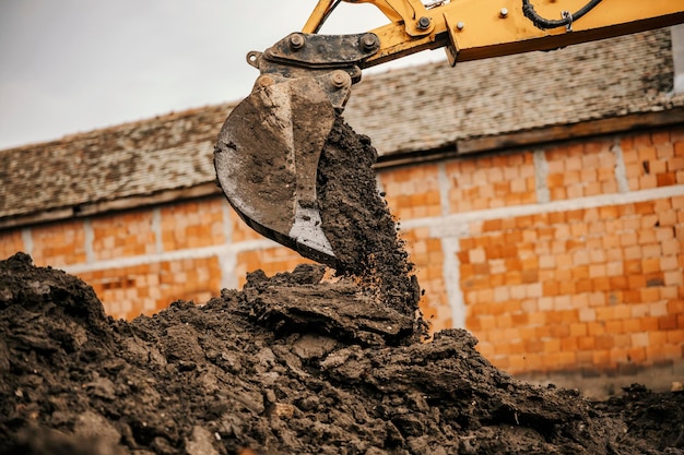 Uma retroescavadeira está derramando solo em uma pilha no canteiro de obras