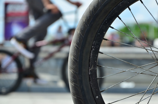 Uma roda de bicicleta de bmx contra o pano de fundo de uma rua turva com ciclistas. conceito de esportes radicais