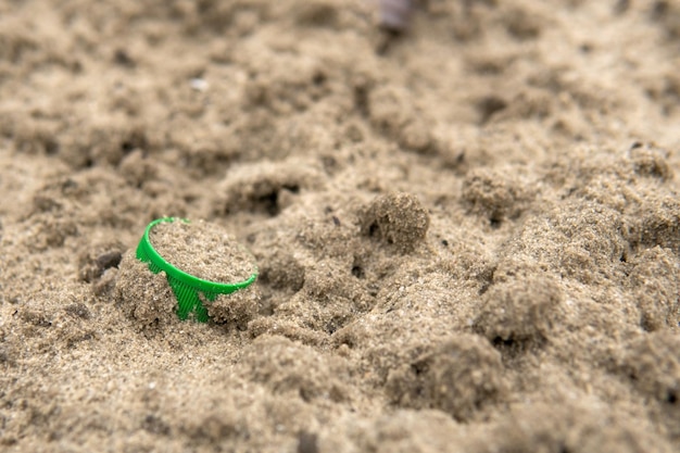 Uma rolha verde de uma garrafa de plástico está na areia Poluição ambiental