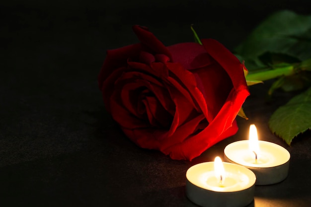 Uma rosa vermelha de rosas com velas em um fundo escuro atmosfera mística dramática do ritual de magia negra o conceito de cartões postais de luto e luto