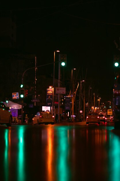 Uma rua onde as luzes vermelhas e verdes são refletidas no chão