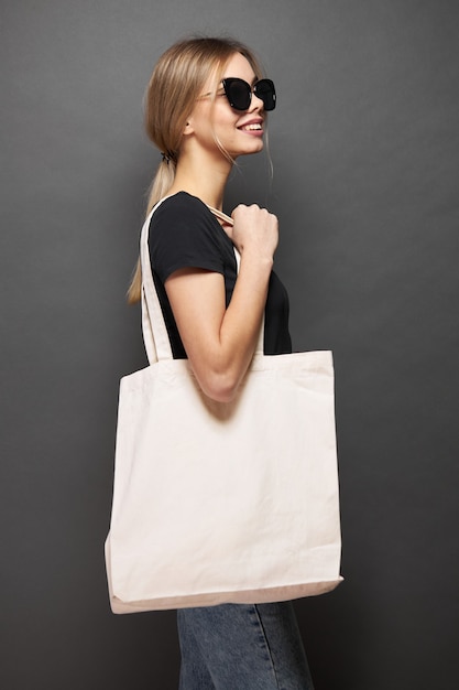 Uma sacola ecológica para maquete é segurada por uma mulher sobre uma textura cinza