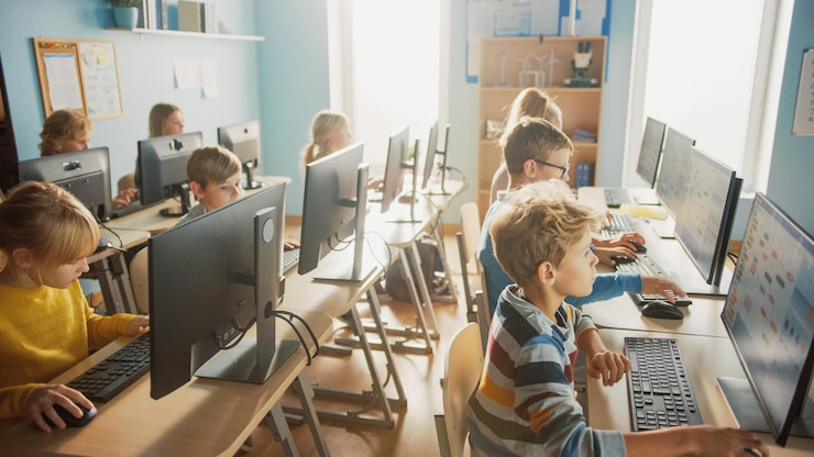 Foto uma sala de aula com uma tela de computador mostrando um grupo de crianças sentadas em carteiras e uma delas é rotulada como uma escola.