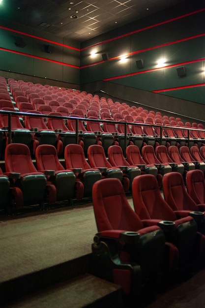 Uma sala de cinema com assentos vermelhos e uma placa verde que diz 'o filme está aqui'