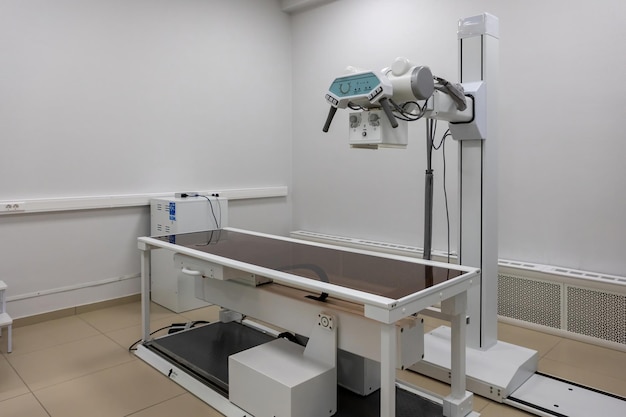 Uma sala de raios X com uma máquina de varredura e uma cama vazia Varredura dos pulmões das articulações do tórax