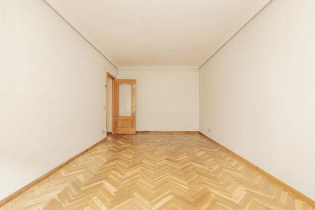 Uma sala grande e vazia em uma casa com piso em parquet