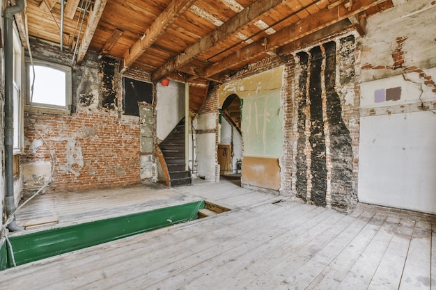 Uma sala vazia com pisos de madeira e paredes de tijolos em uma casa velha que precisa de renovação