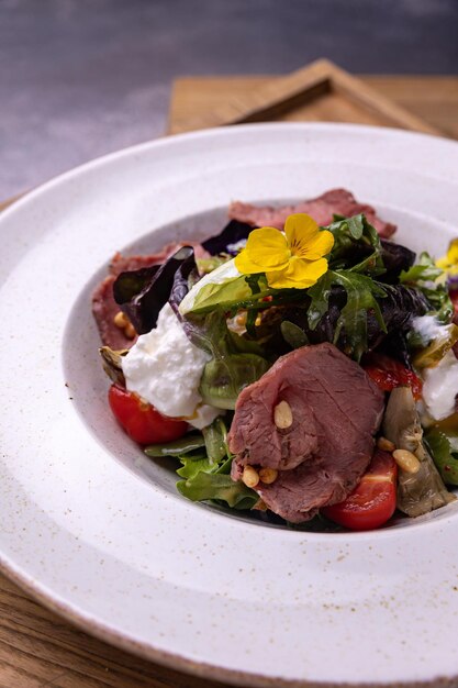 Uma salada com um pedaço de carne e queijo