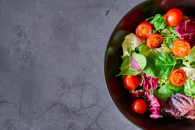 Uma salada de alface tomate alface e escarola em uma placa preta em um fundo de ardósia