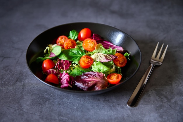 Uma salada de alface tomate alface e escarola em uma placa preta em um fundo de ardósia