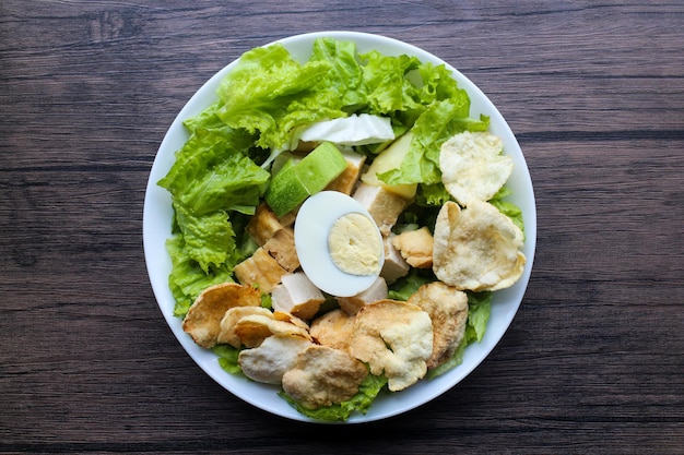 Uma salada vegana verde feita com uma mistura de folhas verdes e vegetais polvilhados com biscoitos e meio ovo cozido