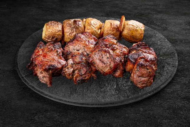 Uma seleção de carnes gourmet grelhadas em uma placa de pedra rústica Kebab de porco com batatas abked
