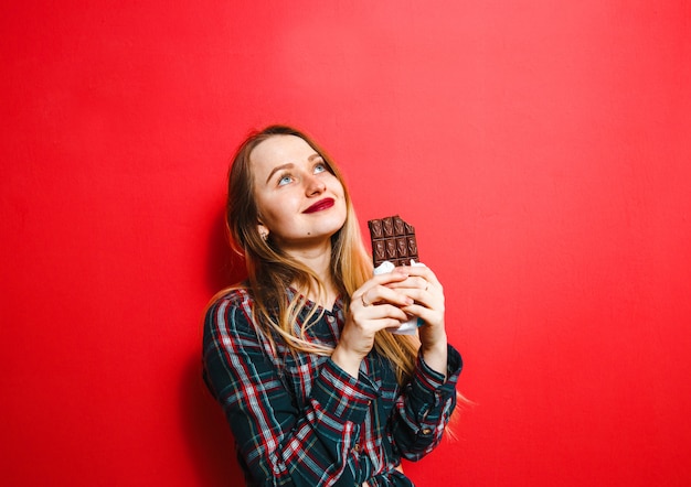 Uma senhora bonita que gosta de chocolate sobre um fundo vermelho.