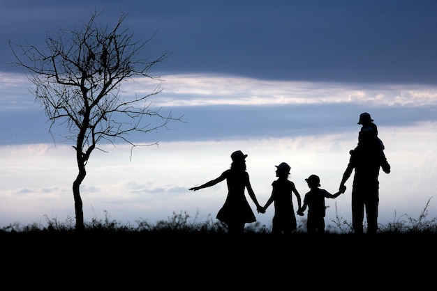 Uma silhueta de família feliz na natureza no fundo do parque