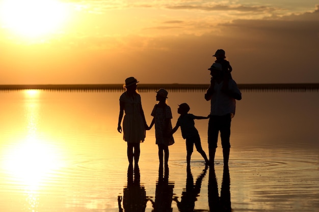 Uma silhueta de família feliz no mar com reflexo no parque na natureza