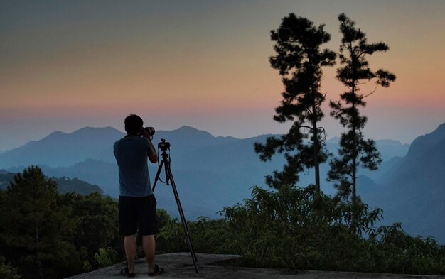 Uma silhueta de fotógrafo com cordilheira no crepúsculo