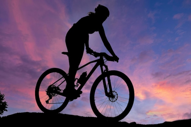 Uma silhueta de um ciclista praticando um passeio de bicicleta em uma montanha